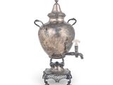 une théière en argent posée sur un socle, avec une bougie dessus
