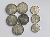 six types de pièces différents sont disposés en cercle sur une surface blanche