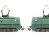 two green trains sitting side by side on a white surface