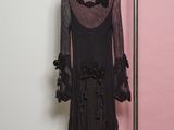 black dress hanging on a hanger in front of a pink wall