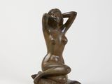 a bronze statue of a woman sitting on a pillow
