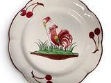 une assiette sur laquelle est peint un coq sur fond blanc
