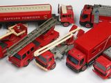 de nombreux camions de pompiers et camions miniatures posés sur une surface blanche