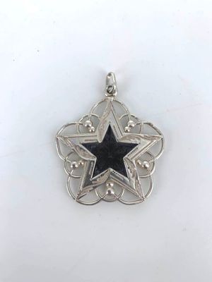 a close up of a star shaped pendant on a white surface