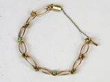 un gros plan d'un bracelet en or orné de perles de turquoise sur un fond blanc