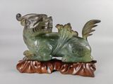 statue représentant un animal vert et marron posée sur un socle en bois
