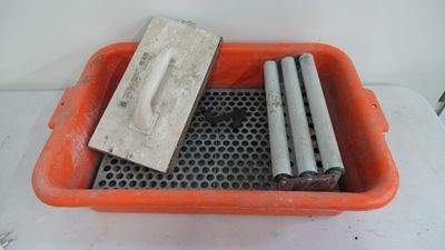 a red container filled with metal pipes and a cement block