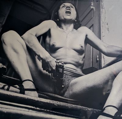 photographie en noir et blanc d'une femme nue assise sous un porche