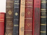 several old books are lined up on a shelf next to each other