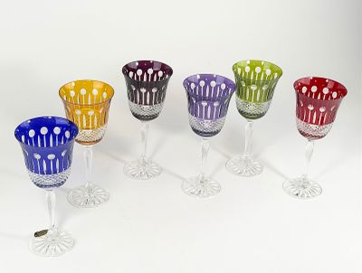 several different colored wine glasses are lined up on a white surface