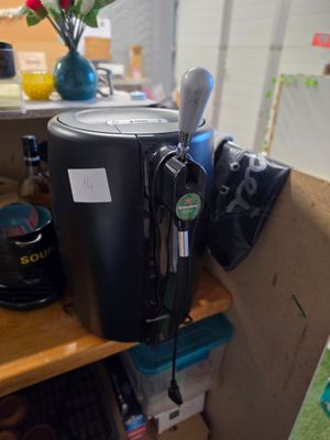 une cafetière noire posée sur une étagère en bois, à côté d'un vase de fleurs