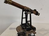 un télescope ancien en laiton posé sur un socle, sur une surface blanche