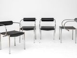 quatre fauteuils en cuir noir aux pieds chromés dans une pièce blanche