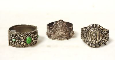 trois bagues en argent ornées de pierres vertes, posées sur un fond blanc