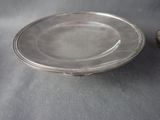 a silver plate on a table next to a silver spoon