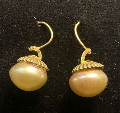 a pair of earrings with pearls on them sitting on a black surface