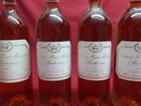 four bottles of wine are lined up in a row on a red background