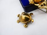 a gold turtle brooch sitting on a table next to a pair of glasses