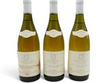 trois bouteilles de vin blanc posées l'une à côté de l'autre sur une surface blanche
