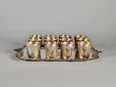 un plateau en argent sur lequel sont posées six tasses et entouré d'une chaîne