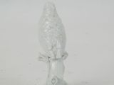 a glass bird sitting on top of a tree stump