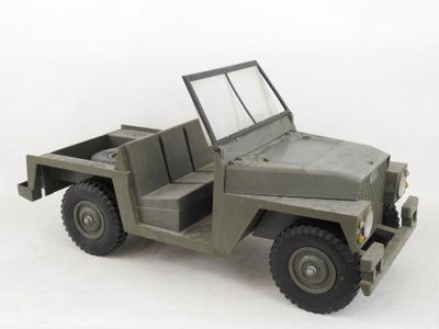 une jeep militaire miniature avec un plateau, posée sur une surface blanche