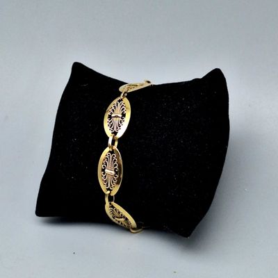 un gros plan d'un bracelet en or posé sur un coussin noir