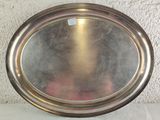 a silver plate sitting on a table with a pink flower in front of it