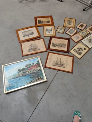 many framed pictures on the floor next to a person ' s feet