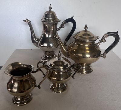 trois théières en argent et un pichet posés sur une table