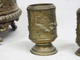 three antique brass vases sitting on top of a white surface
