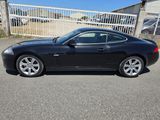une Jaguar noire garée sur un parking, près d'une clôture