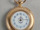 une montre de poche en or avec un cadran blanc sur une surface blanche