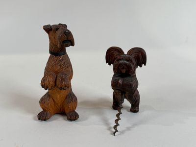 two small wooden sculptures of dogs on a white surface