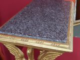 une table dorée avec un plateau en marbre, posée sur une chaise rouge