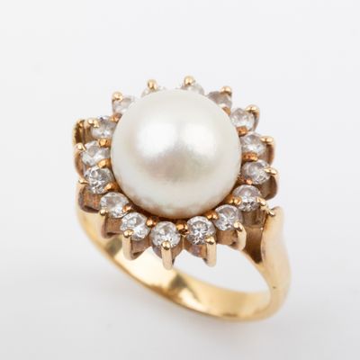 a close up of a pearl and diamond ring on a white background