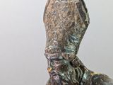 statue of a man with a hat and a beard sitting on a rock