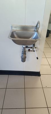 un lavabo dans un coin de la salle de bains, avec un robinet fixé au mur