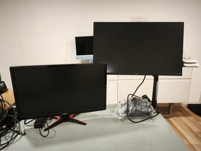 two monitors sitting on a table in a room