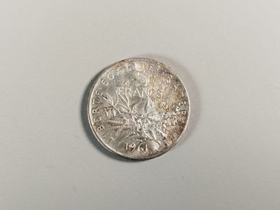 une pièce d'argent posée sur une surface blanche, sur fond blanc