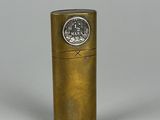 un vieux briquet en laiton avec un capuchon métallique posé sur une surface blanche