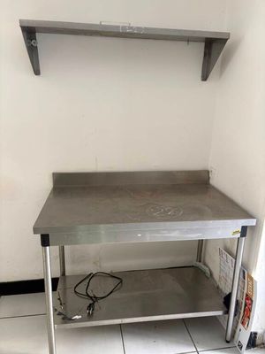 une table de travail en acier inoxydable surmontée d'une étagère