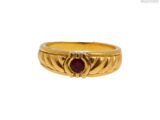 gros plan d'une bague en or avec une pierre en rubis