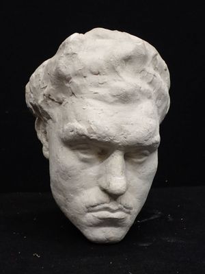 a white sculpture of a man ' s head on a black surface