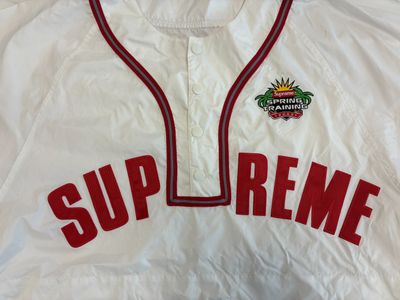 white supreme baseball jersey with red trim and supreme logo on the chest
