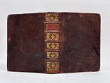 an old brown book with gold trim sitting on top of a white surface