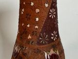 a brown vase sitting on a table with a white wall in the background