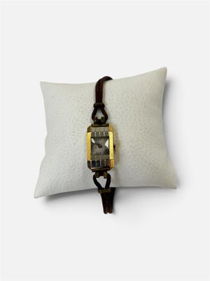 une photo d'une montre-bracelet posée sur un oreiller, sur une surface blanche