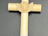 une croix en bois ornée d'ailes d'ange, posée sur un fond noir