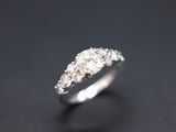 a close up view of a three stone diamond ring on a black surface